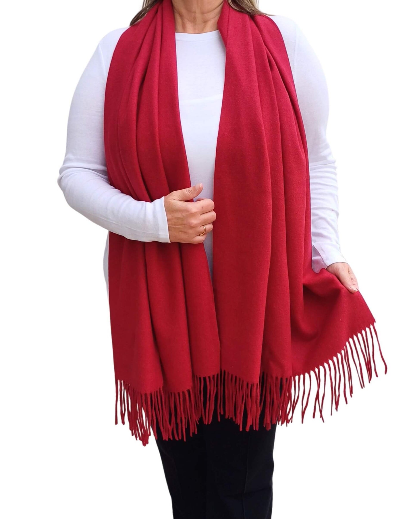 Aurora's Array: Woman models a soft, warm wine red, crimson wool blend scarf with fringed edges, draped around her neck and shoulders.