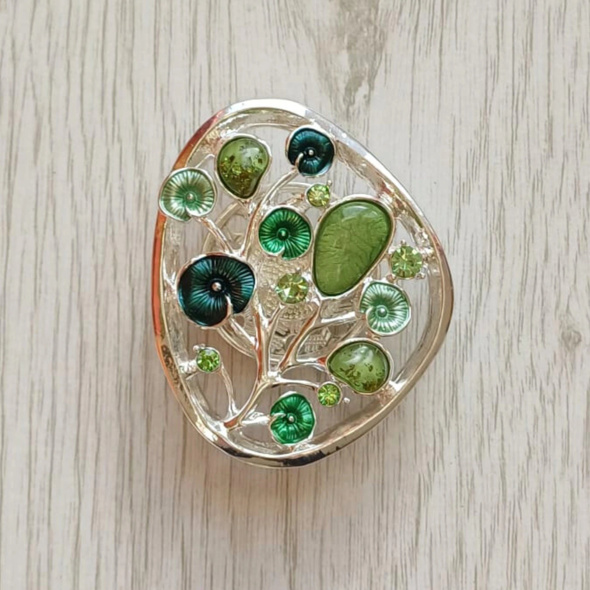 Green Tree of Bloom magnetic brooch with painted metal finish on pale wood surface