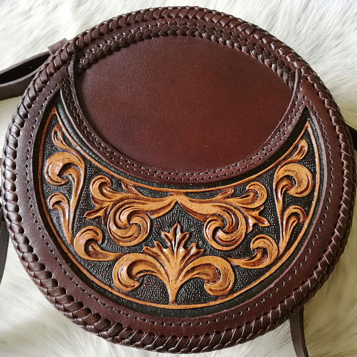 Front-facing image of hand-tooled leather crossbody bag with ornate floral pattern
