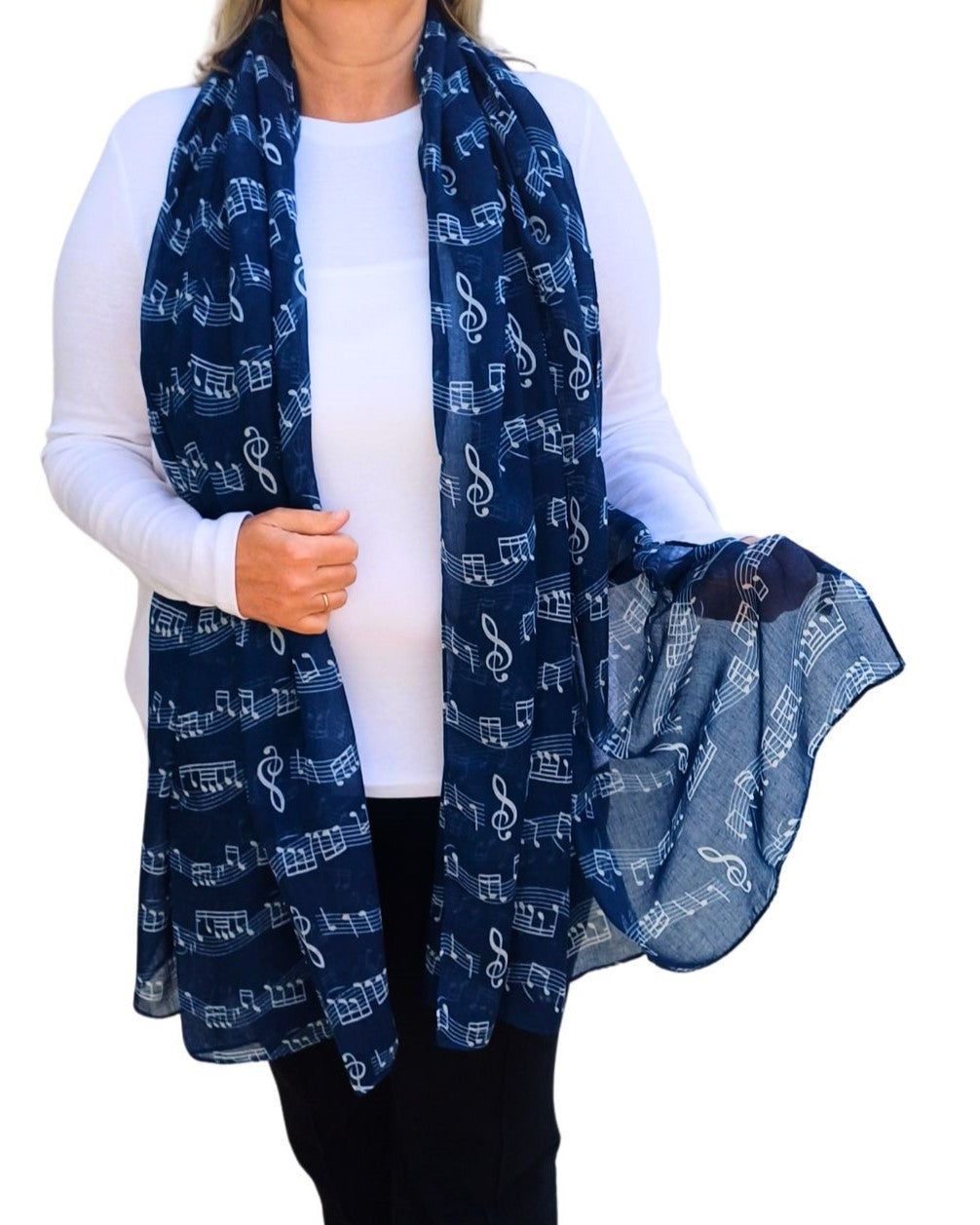 Soft navy blue scarf decorated with an all-over design of white musical symbols like notes, clefs, and staves. Lightweight, flowing fabric.