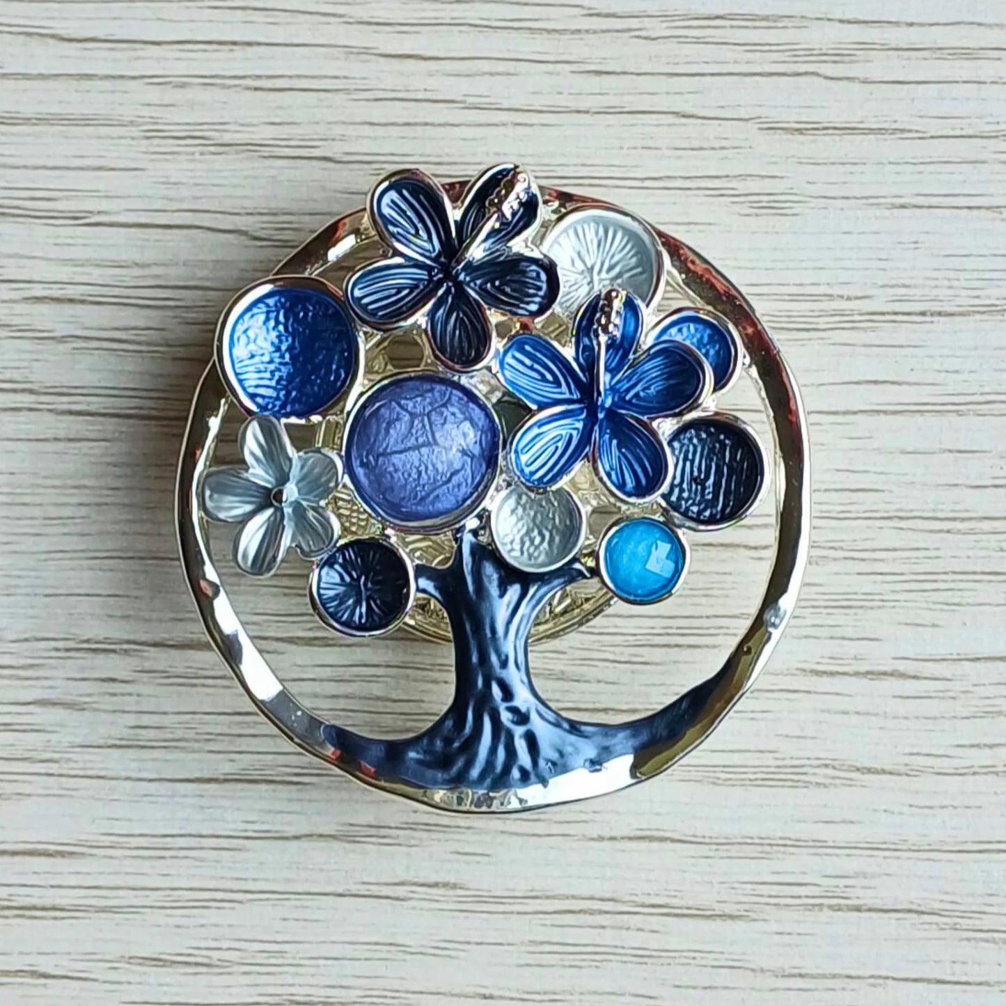 Blossom tree magnetic brooch in blue decorative painted finish on a wooden surface.