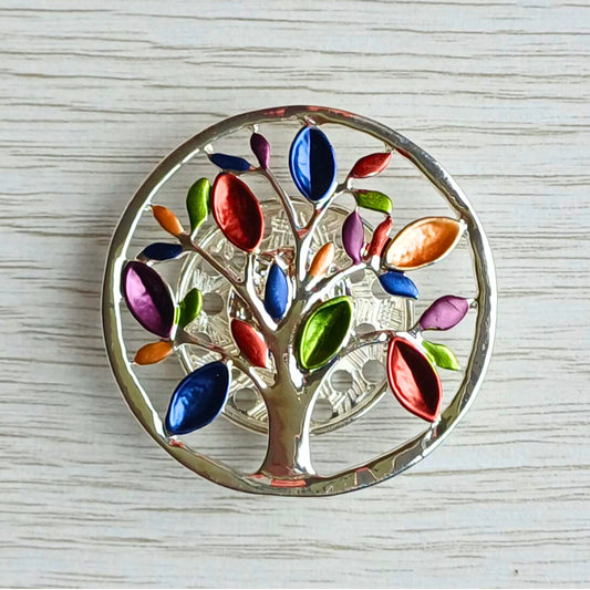 Tree of Life magnetic brooch with multicoloured leaves on a wooden surface.