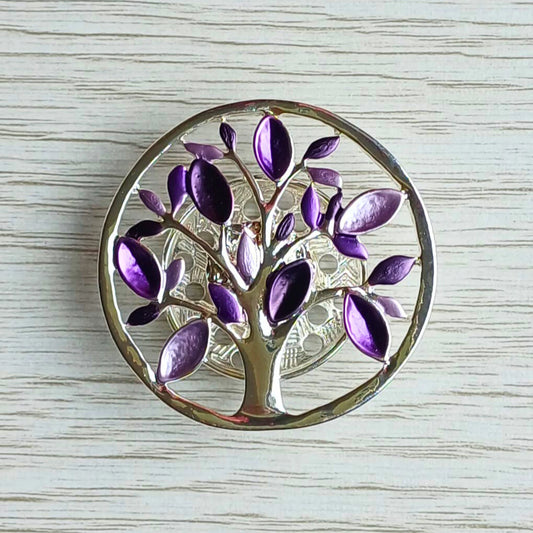 Tree of Life magnetic brooch with purple leaves on a wooden surface.