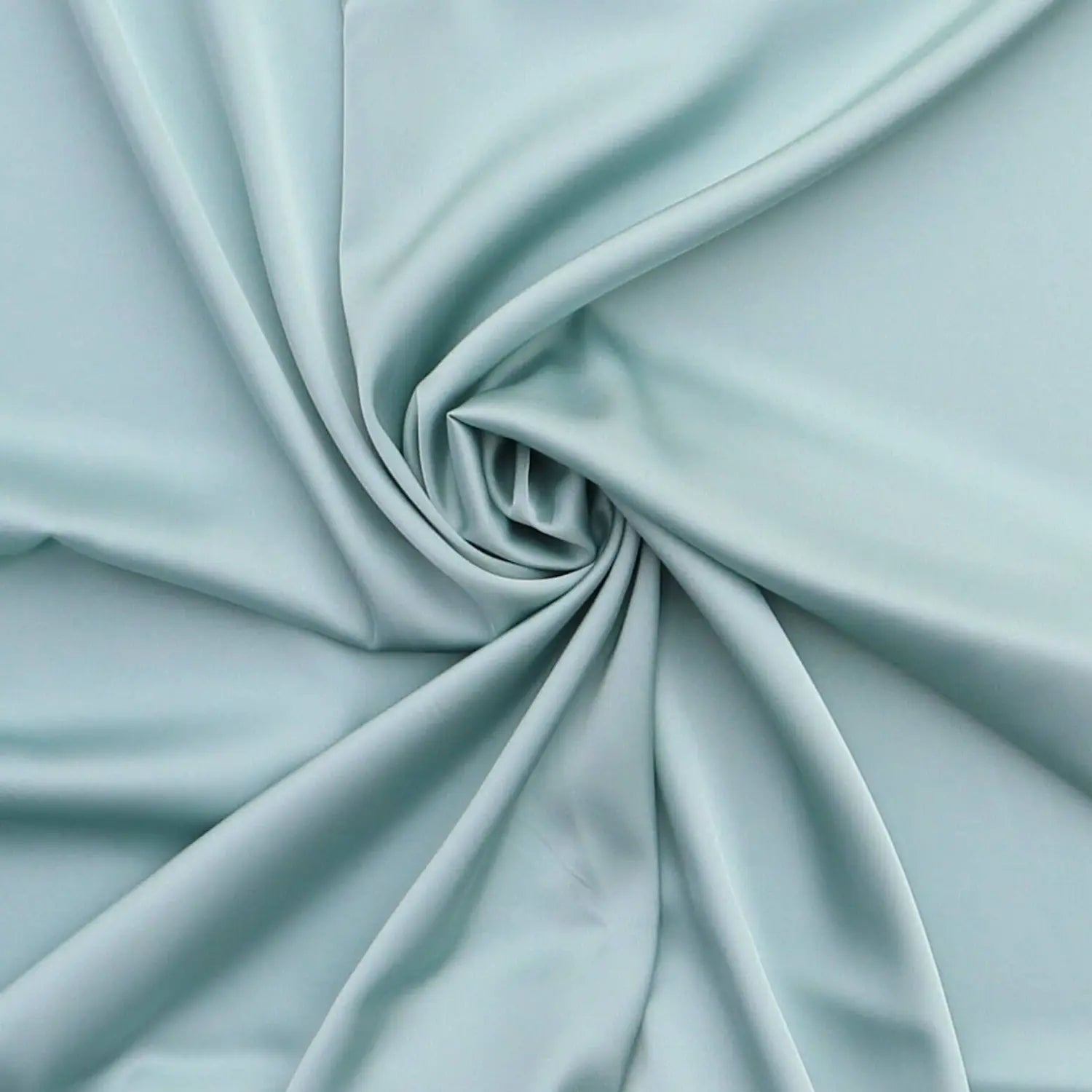 Close-up of sage green satin fabric with a soft silky texture, gently swirled to show the sheen and drape