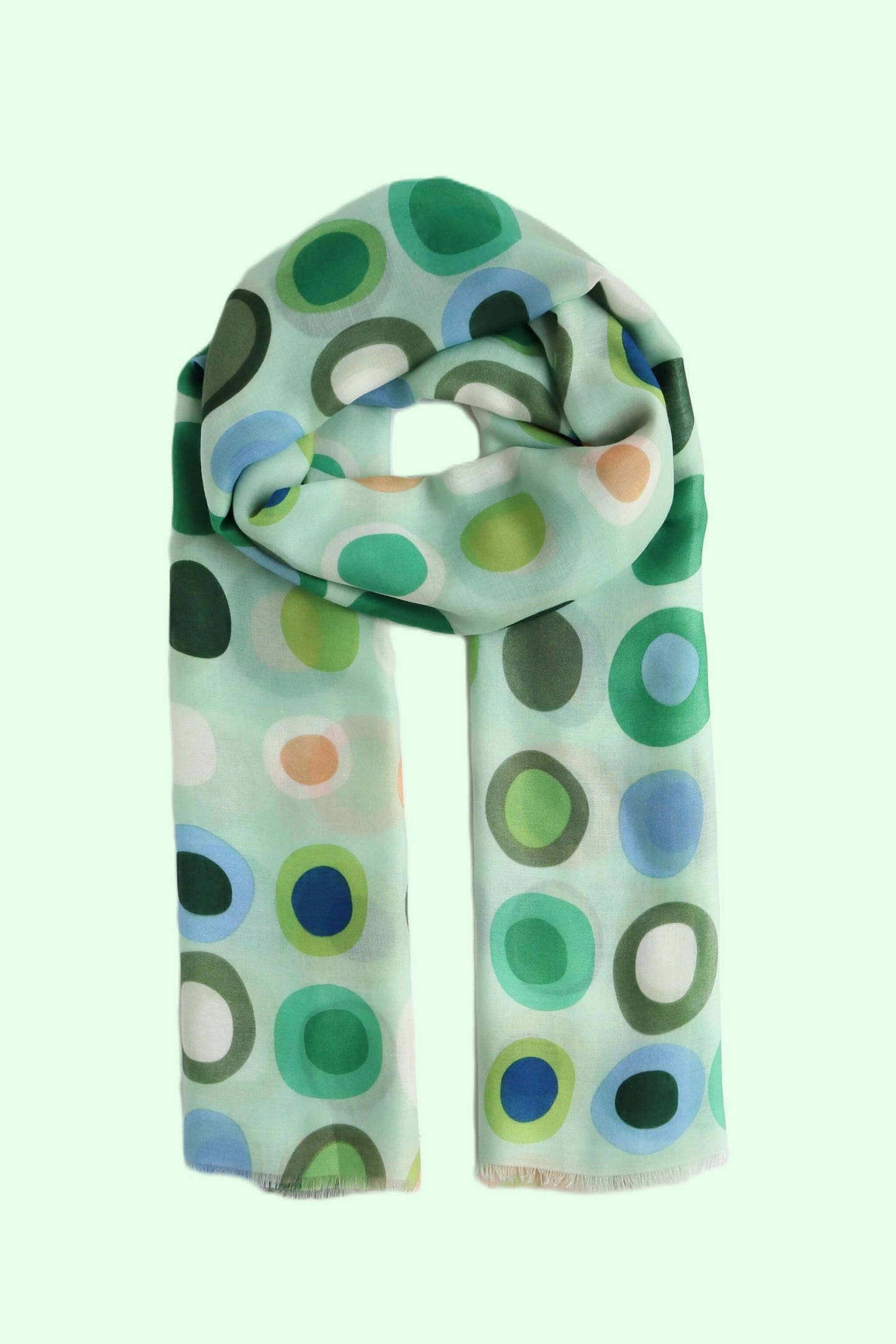 Pale aqua scarf with a retro circle and oval pattern in shades of green, blue, and peach. Soft, lightweight fabric with a subtle fringe.