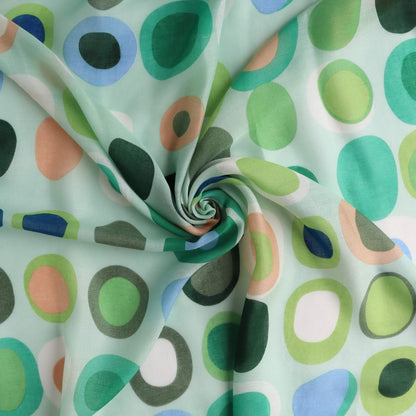 Pale aqua beach wrap fabric with a fun circle and oval pattern in green, peach, blue, and white. Sheer, breezy textile with a central swirl.