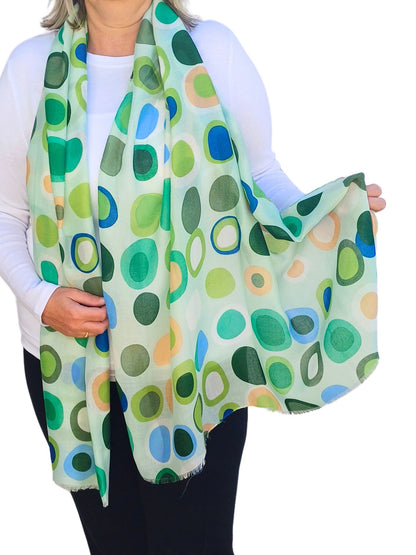 Pale aqua scarf with a retro circle and oval pattern in shades of green, blue, and peach. Soft, flowing fabric with a delicate fringe.