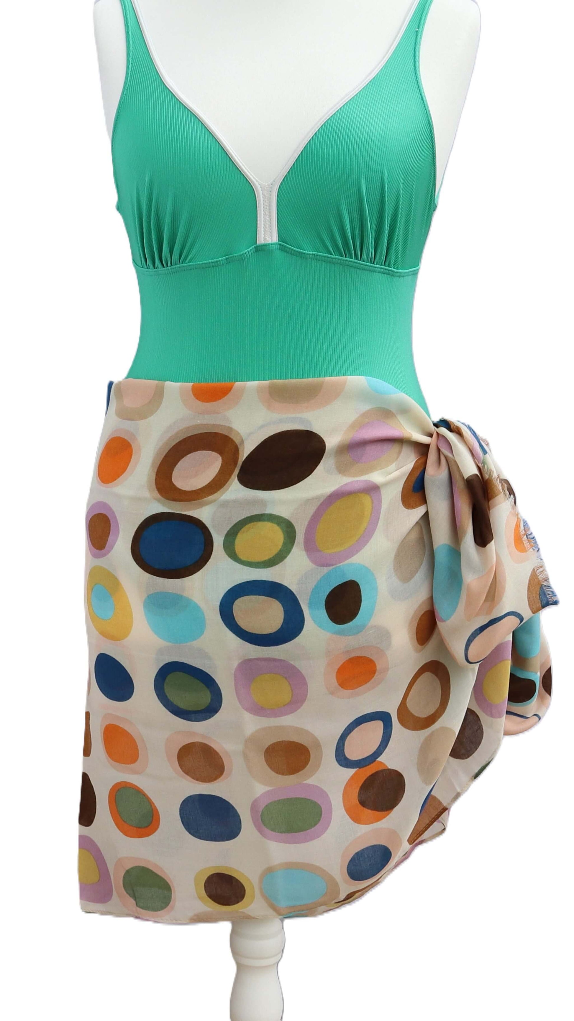 Off-white beach cover-up featuring a retro oval and circle print in brown, orange, yellow, blue, and pink. Light, airy fabric tied in a knot.