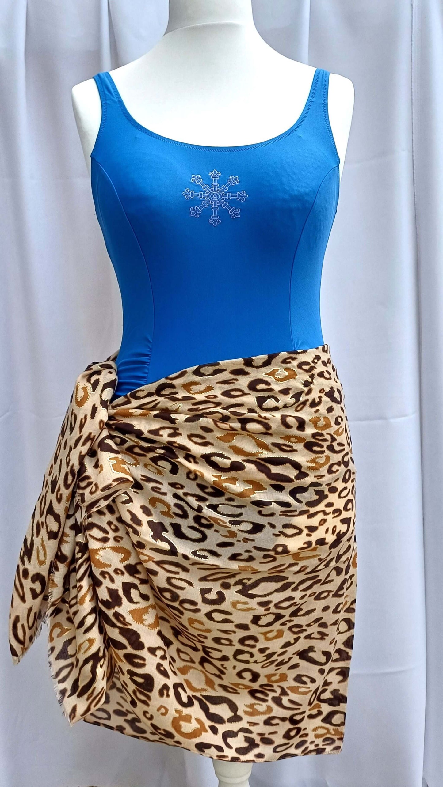 Classic leopard print beach wrap in tan, brown, and black, knotted at the hip. Lightweight, flowing fabric with a slightly sheer quality.