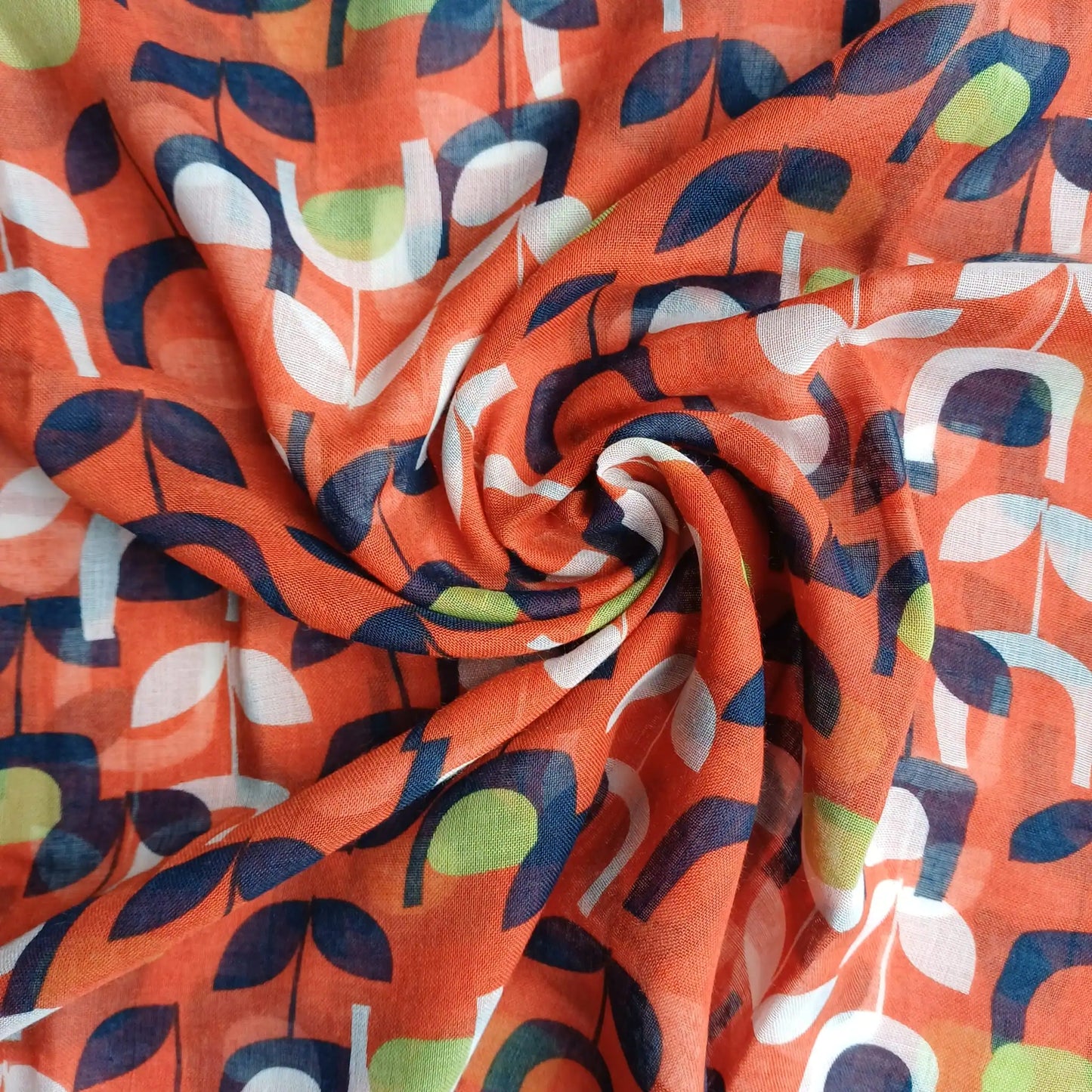 Burnt orange abstract floral scarf styled in spiral fabric detail close up