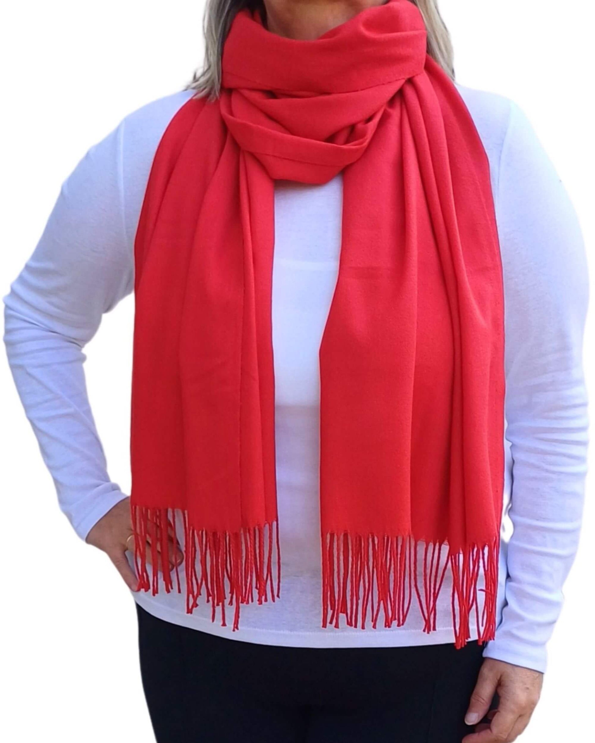Aurora's Array: Woman models a soft, warm bright red wool blend scarf with fringed edges, wrapped around her neck.