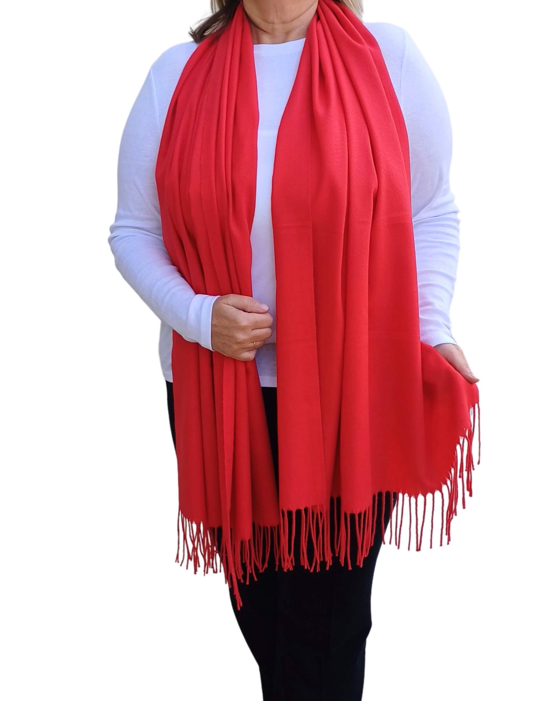 Aurora's Array: Woman models a soft, warm bright red wool blend scarf with fringed edges, draped around her neck and shoulders.