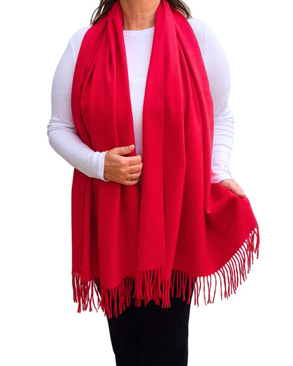 Aurora's Array: Woman models a soft, warm bright red wool blend scarf with fringed edges, draped around her neck and shoulders.