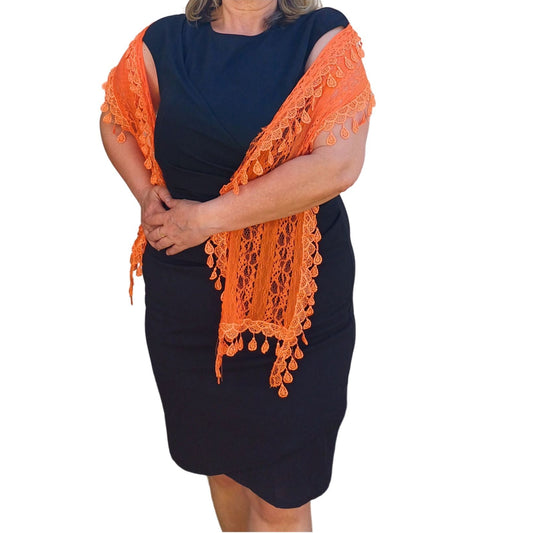 Aurora's Array: Woman models a vibrant orange lace scarf with a delicate leaf-like pattern and fringed edges.