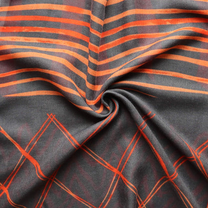 Aurora's Array: Close-up of a soft, lightweight scarf with a grey and a vibrant orange geometric print featuring stripes and zigzags.