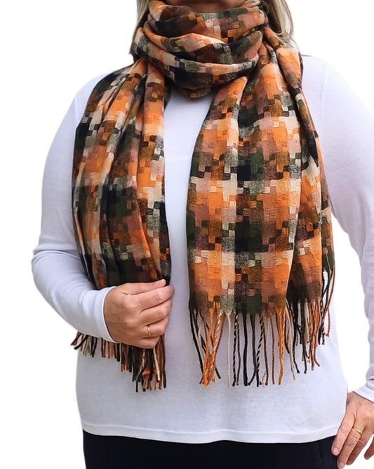 Aurora's Array: Woman models a warm, patterned winter scarf in shades of orange, brown, black, and cream with fringed edges, wrapped around her neck.