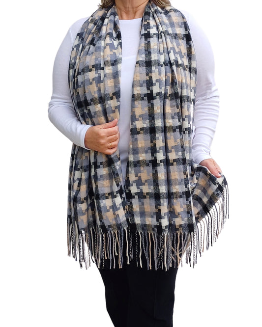 Aurora's Array: Woman models a soft, oversized plaid scarf in shades of black, grey, cream, and a hint of peach with fringed edges.