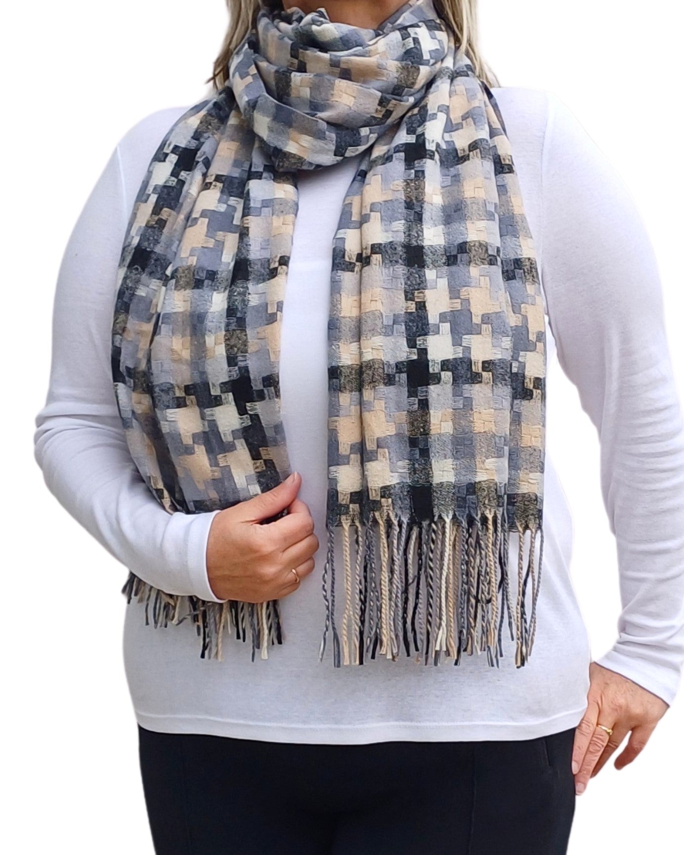 Aurora's Array: Woman models a soft, patterned winter scarf in shades of black, grey, cream, and a hint of peach with fringed edges, wrapped around her neck.
