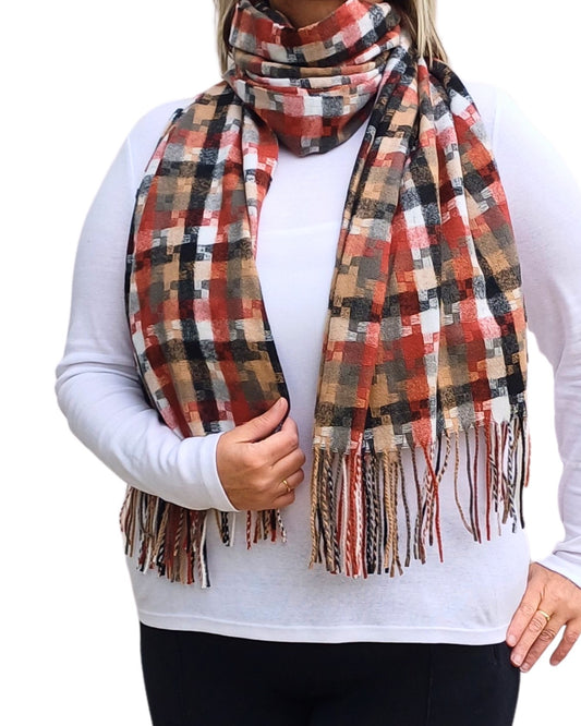 Aurora's Array: Woman models a soft, patterned winter scarf in shades of rust, brown, black, cream, and red with fringed edges, wrapped around her neck.