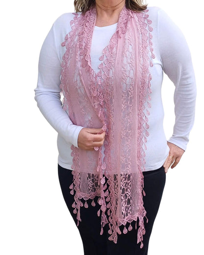 Aurora's Array: Woman models a soft pink lace scarf with a delicate leaf-like pattern and fringed edges.