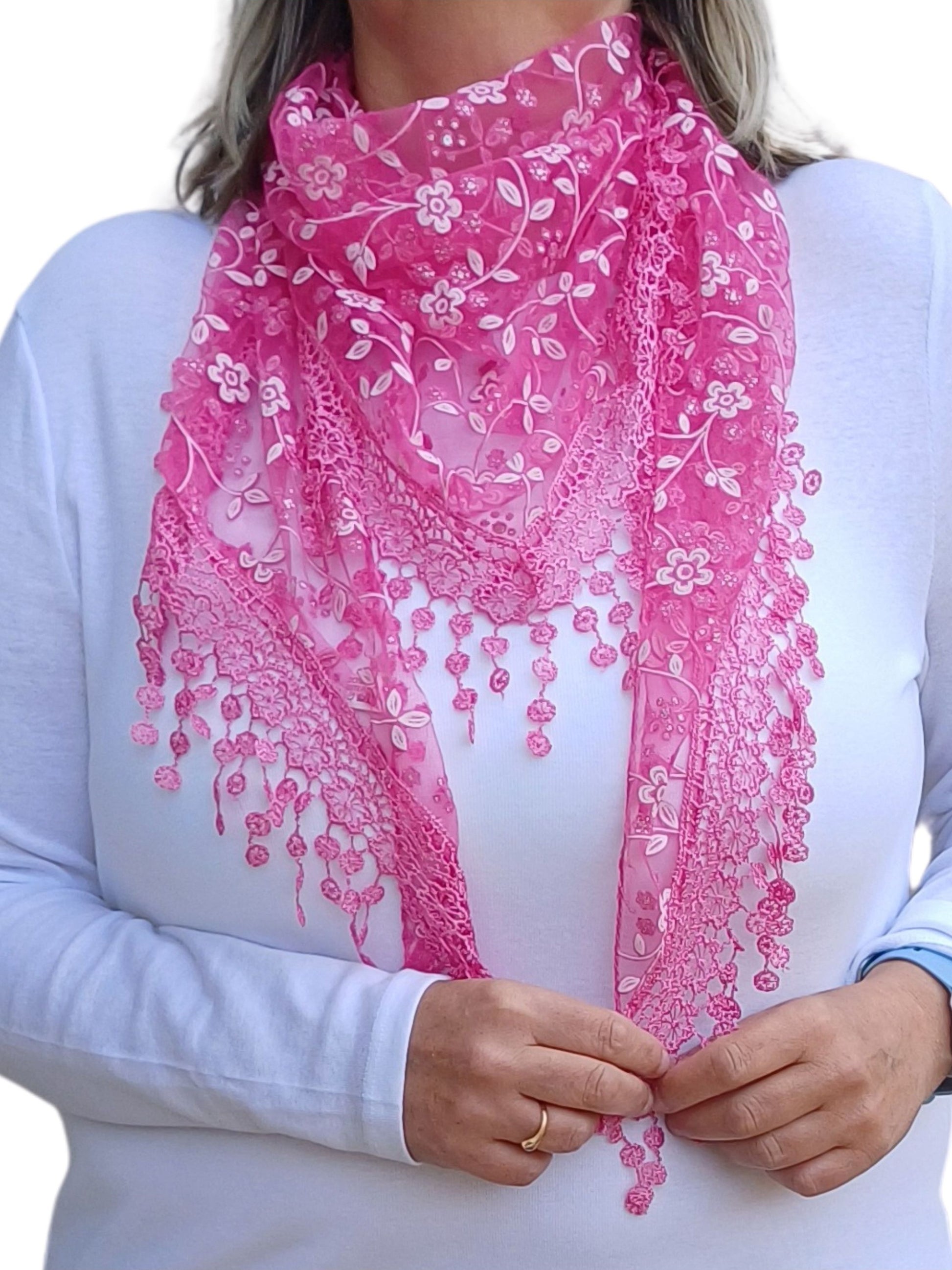  Aurora's Array Glitter Triangle Scarf: A woman wearing a bright fuchsia pink lace scarf with floral embroidery and delicate dangling lace details. The scarf is styled in a triangular shape over a plain white long-sleeve top.