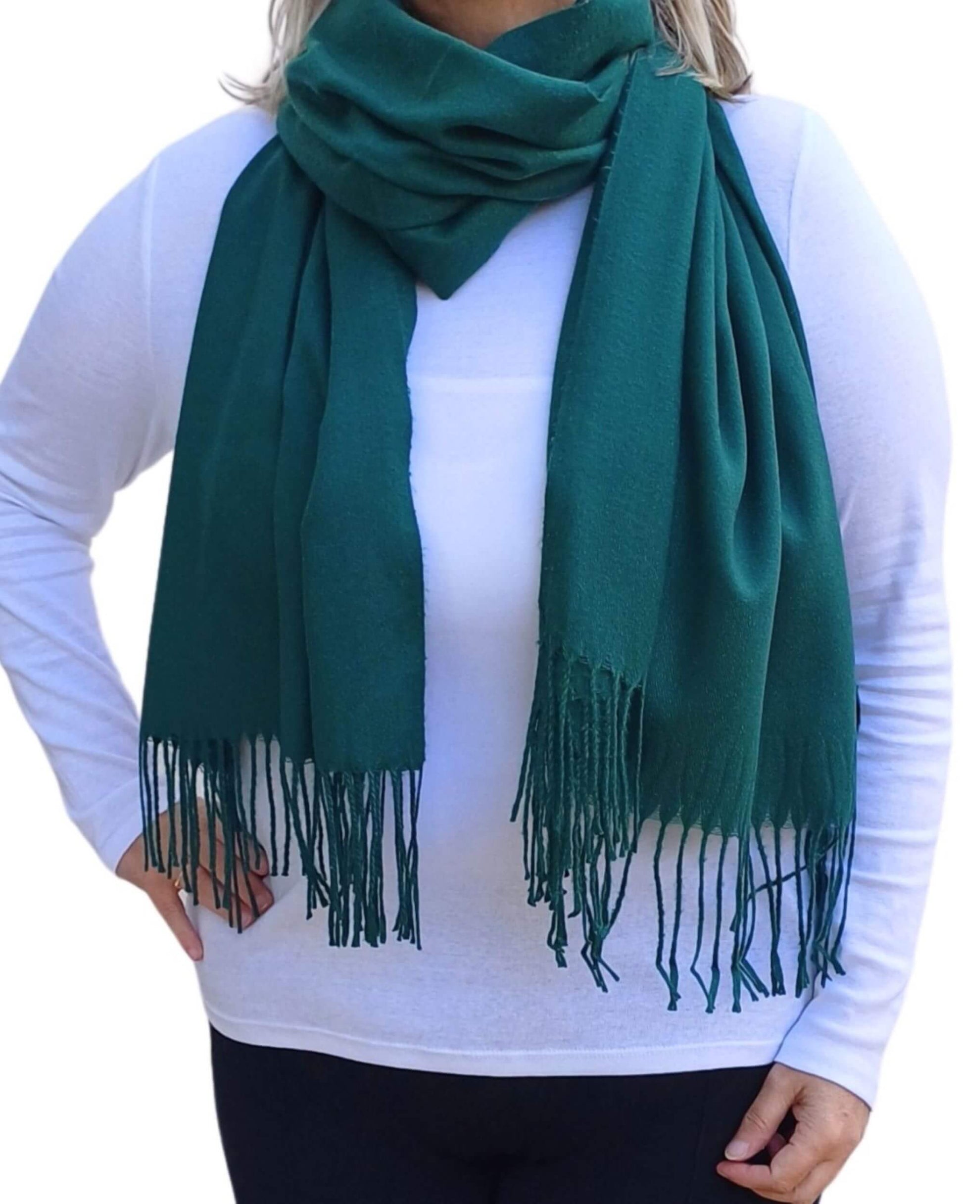 Aurora's Array: Woman models a soft, warm forest green wool blend scarf with fringed edges, wrapped around her neck.