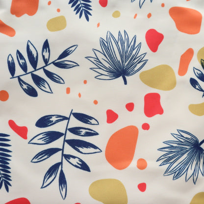 Close-up of a cream crossbody bag's material: a modern abstract leaf and geometric design in navy, red, and yellow. Textured fabric detail.