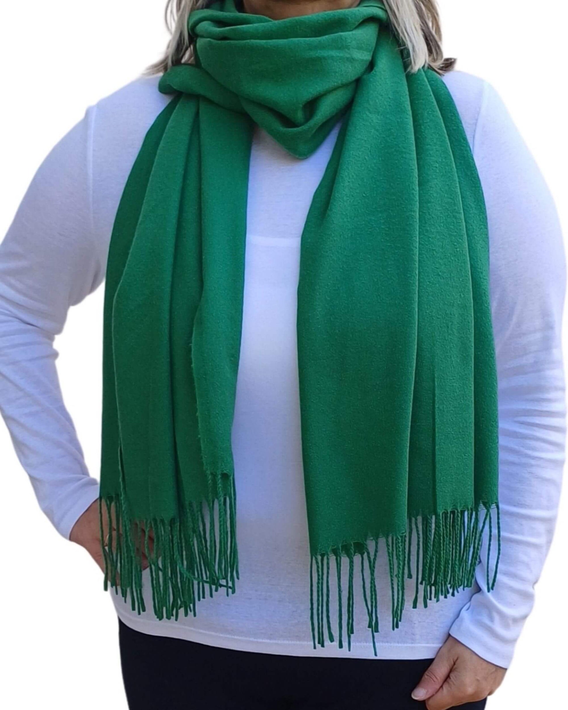 Aurora's Array: Woman models a soft, warm green wool blend scarf with fringed edges, wrapped around her neck.
