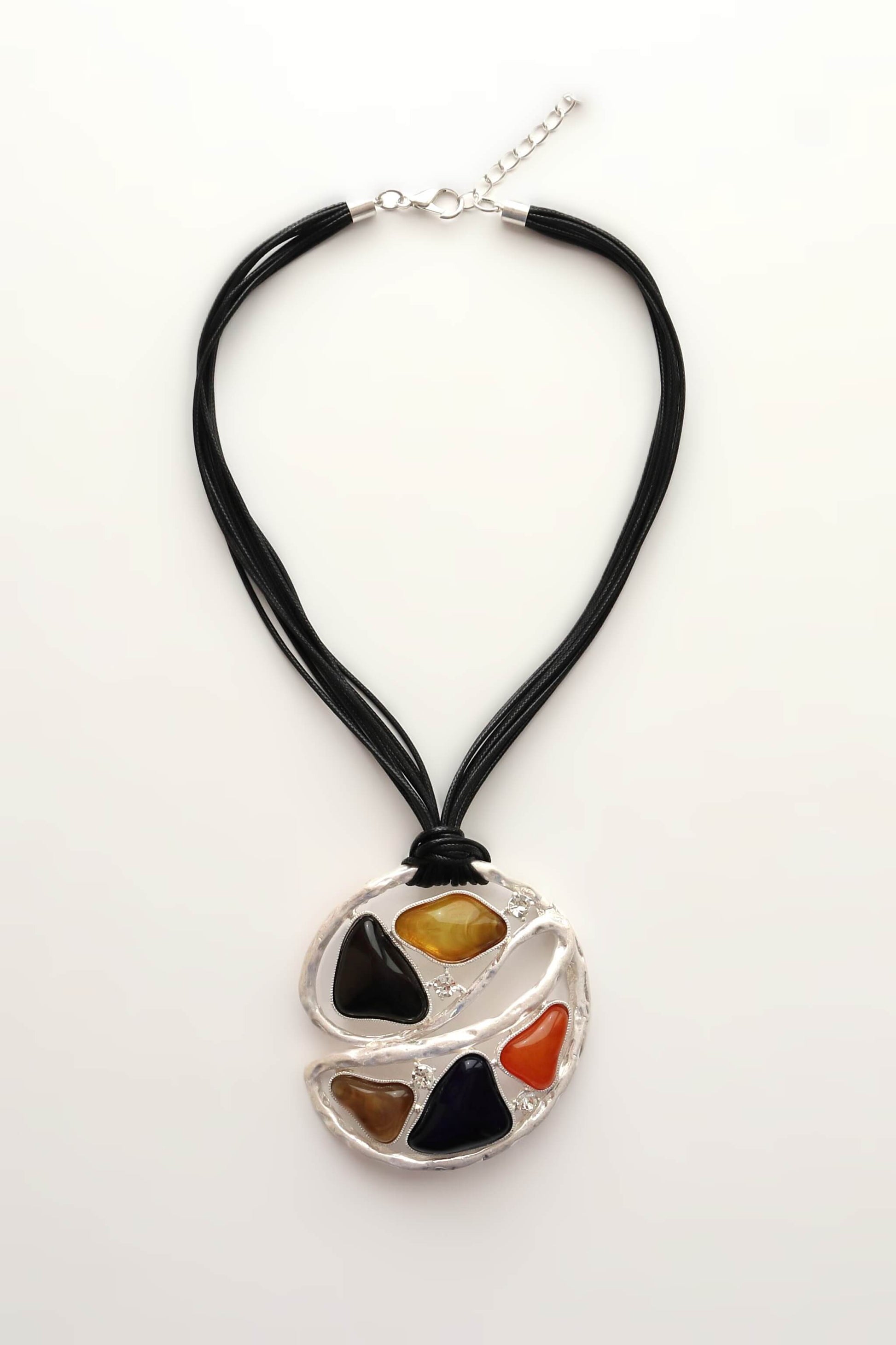 Abstract statement necklace with black cords and a silver-tone geometric pendant. Features colourful resin details and small clear stones. Unique design.