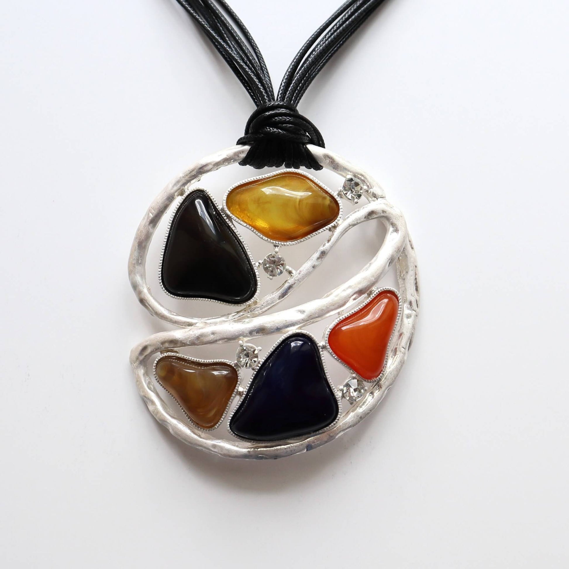 Geometric statement necklace with black cords. Features colourful resin pieces and small clear stones in a textured silver-tone abstract design.