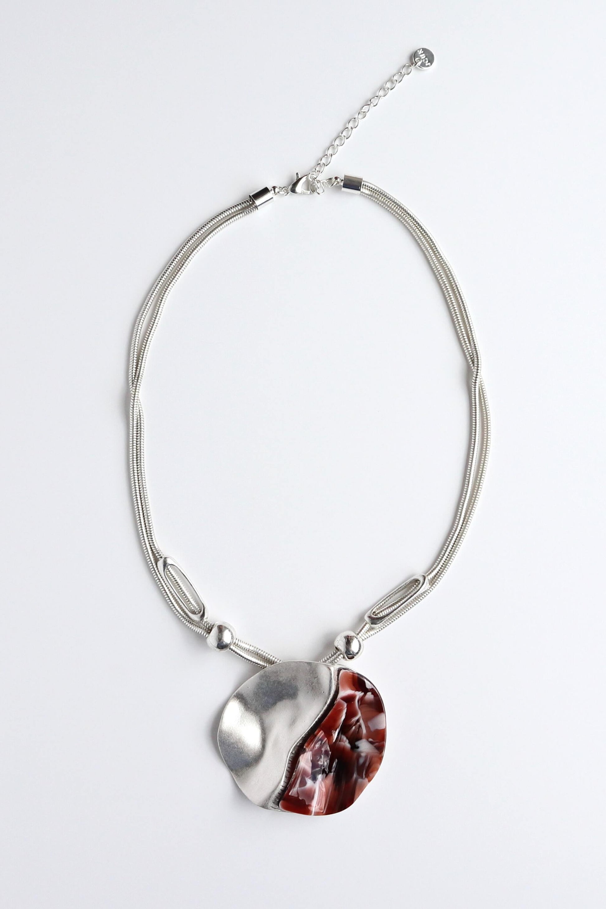 Silver-toned necklace with multiple strands and a unique pendant featuring a textured silver side and a swirling red and white design. Adjustable clasp.