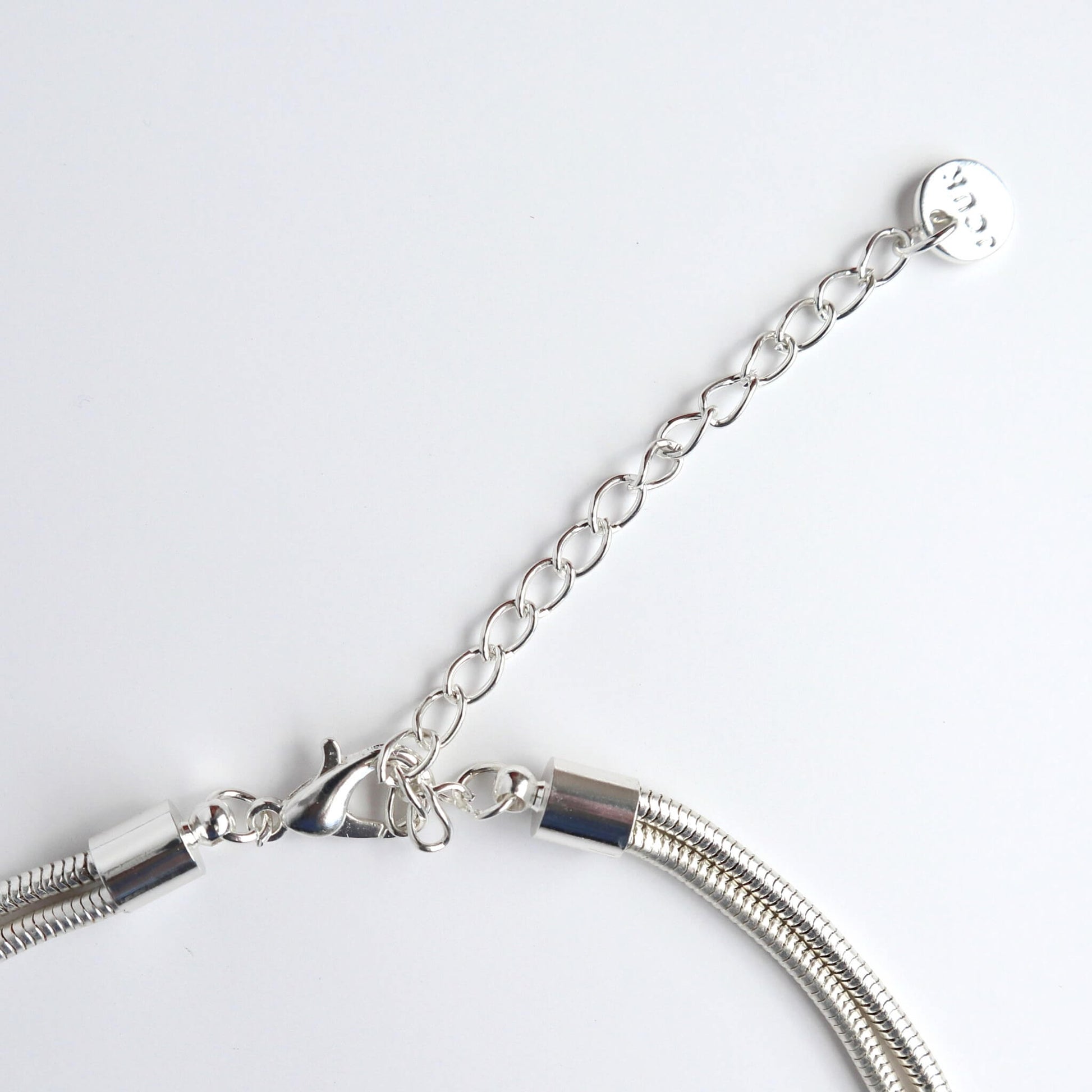 Close-up of a silver-toned necklace clasp, extender chain, and the ends of the multi-strand snake chain. Lobster claw closure.