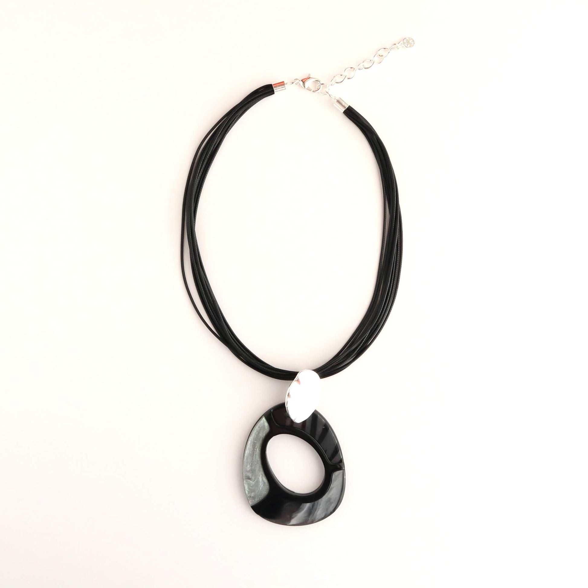 Modern statement necklace with a glossy black and grey swirl pendant. Features a brushed silver oval accent and multiple black cords with a silver clasp.