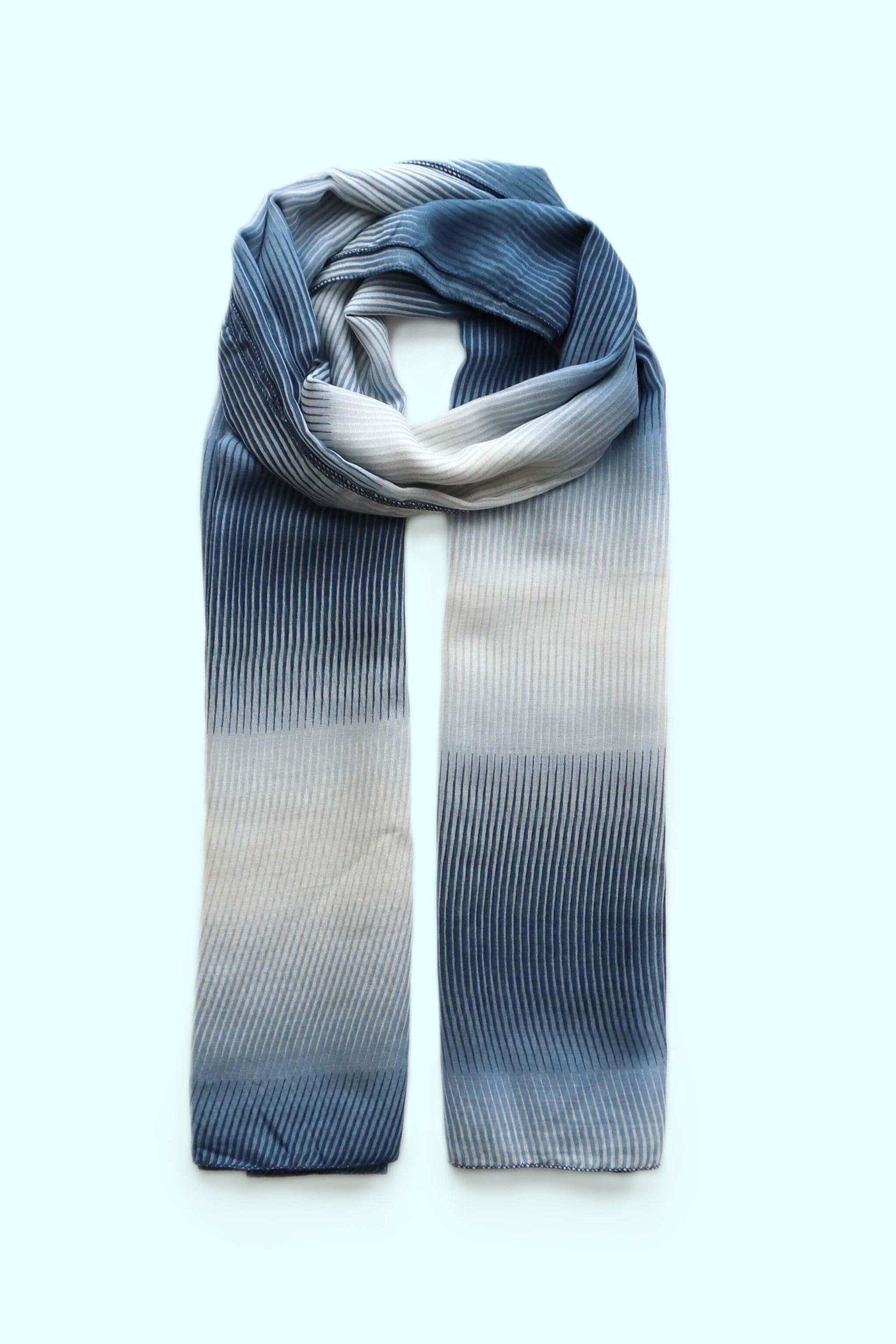 Soft, flowing scarf with a textured stripe pattern and an ombre effect shifting from deep indigo to light silver-grey.