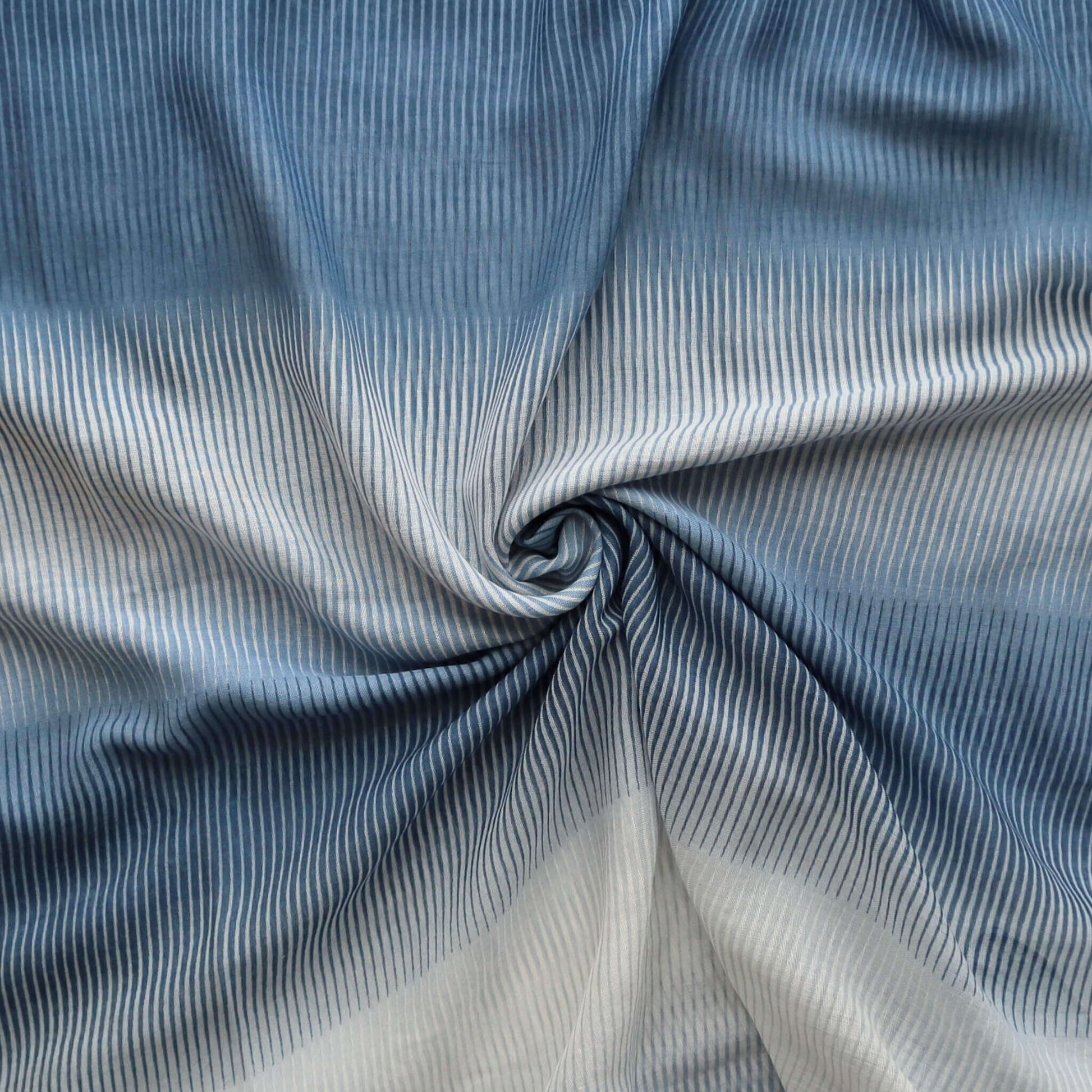 Lightweight scarf fabric with an ombre effect transitioning from deep blue to white, featuring a textured, flowing stripe pattern.