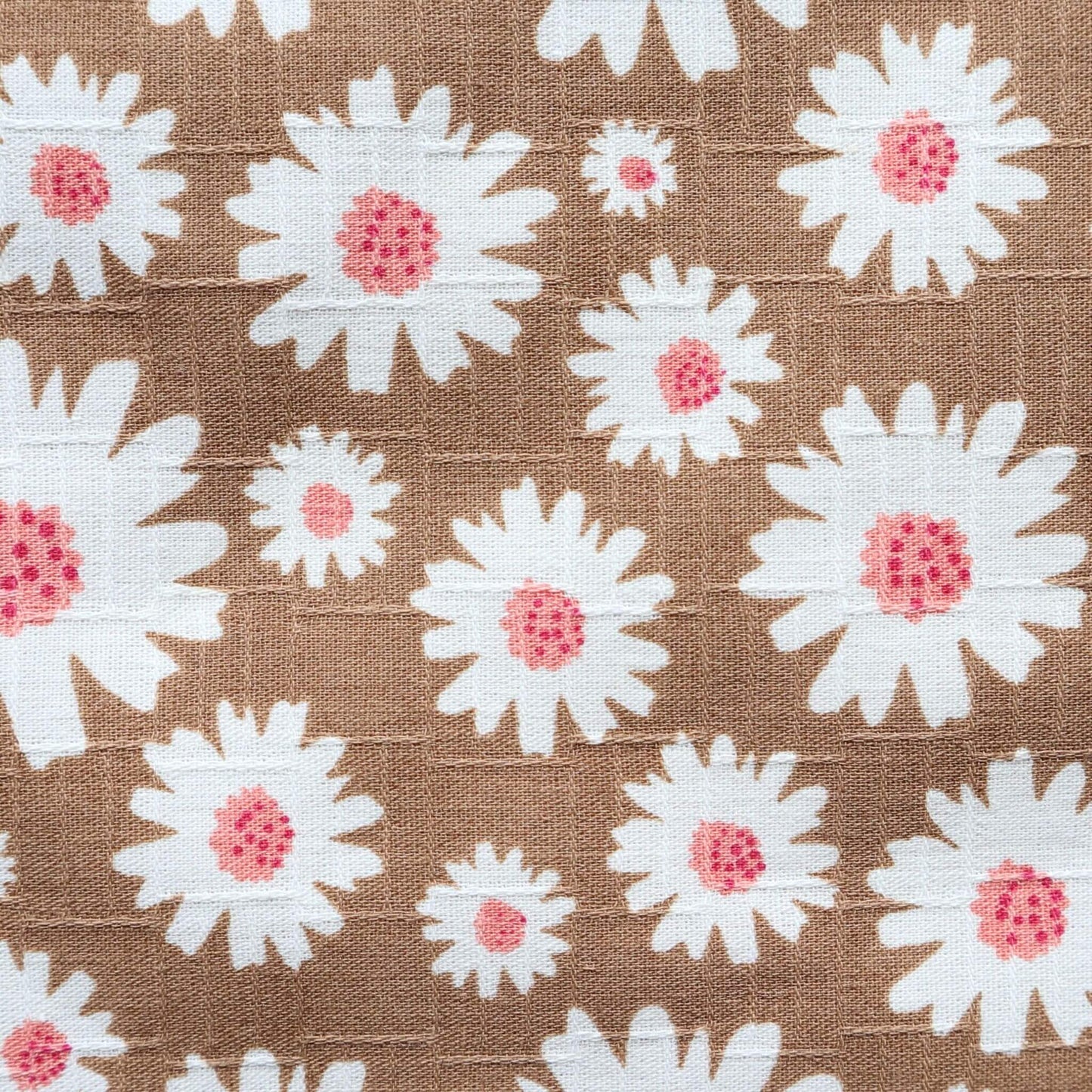 Detailed view of a light brown fabric displaying a repeating pattern of white daisies with textured pink centers.