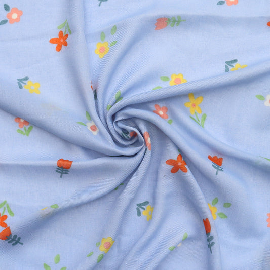 Aurora's Array: Swirls of soft blue fabric of a scarf with a delicate pattern of small orange and yellow flowers with green leaves.