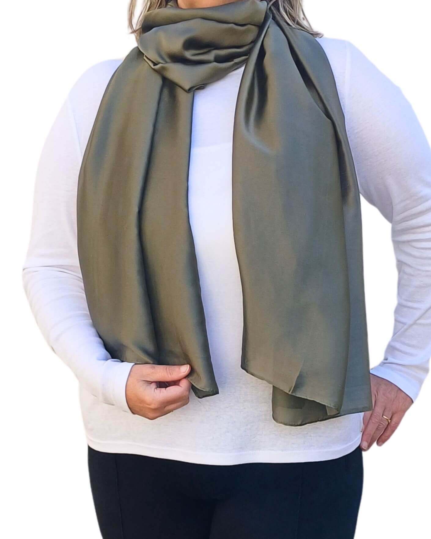Aurora's Array Elegant Satin Shawl: Woman models a soft, khaky green silky scarf wrapped around her neck over a white top.