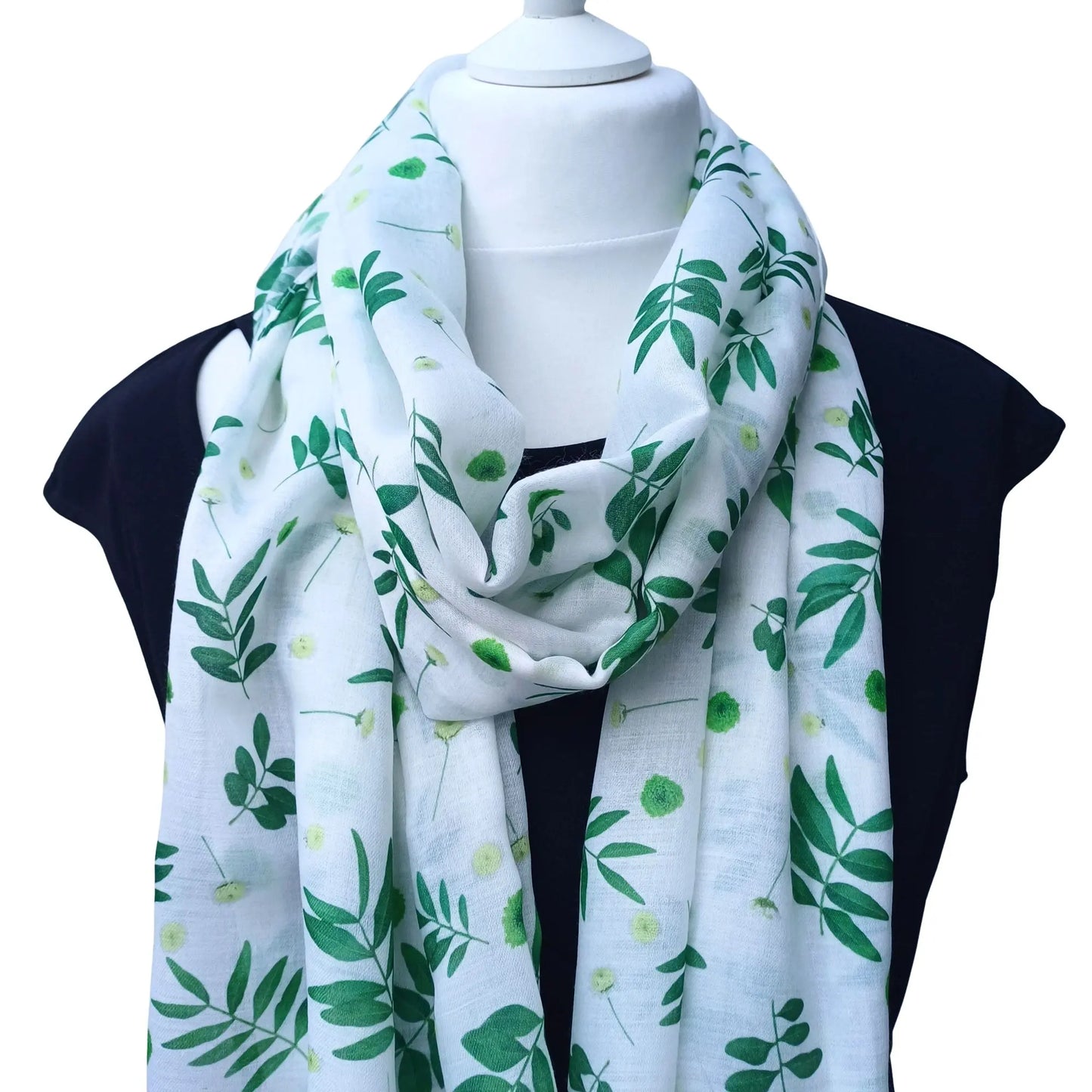 White scarf with green leaf pattern draped over a mannequin on a white background