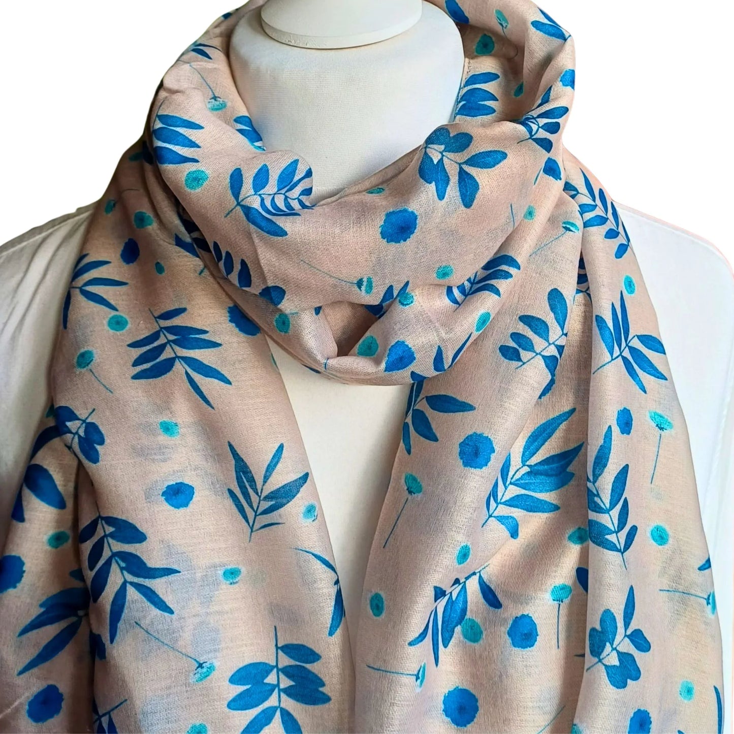 Beige scarf with blue floral pattern draped over a mannequin on a white background