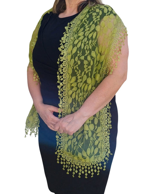 Aurora's Array: Woman models a vibrant green lace scarf with a delicate leaf pattern and fringed edges.