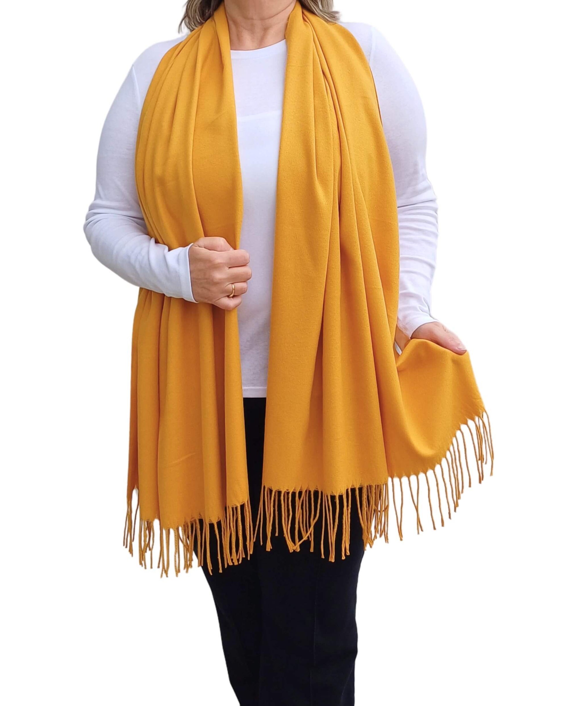 Aurora's Array: Woman models a soft, warm mustard yellow wool blend scarf with fringed edges, wrapped around her neck.