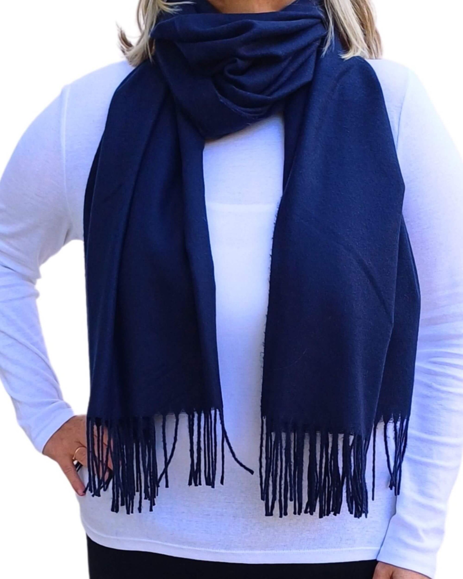 Aurora's Array: Woman models a soft, warm navy blue wool blend scarf with fringed edges, wrapped around her neck.