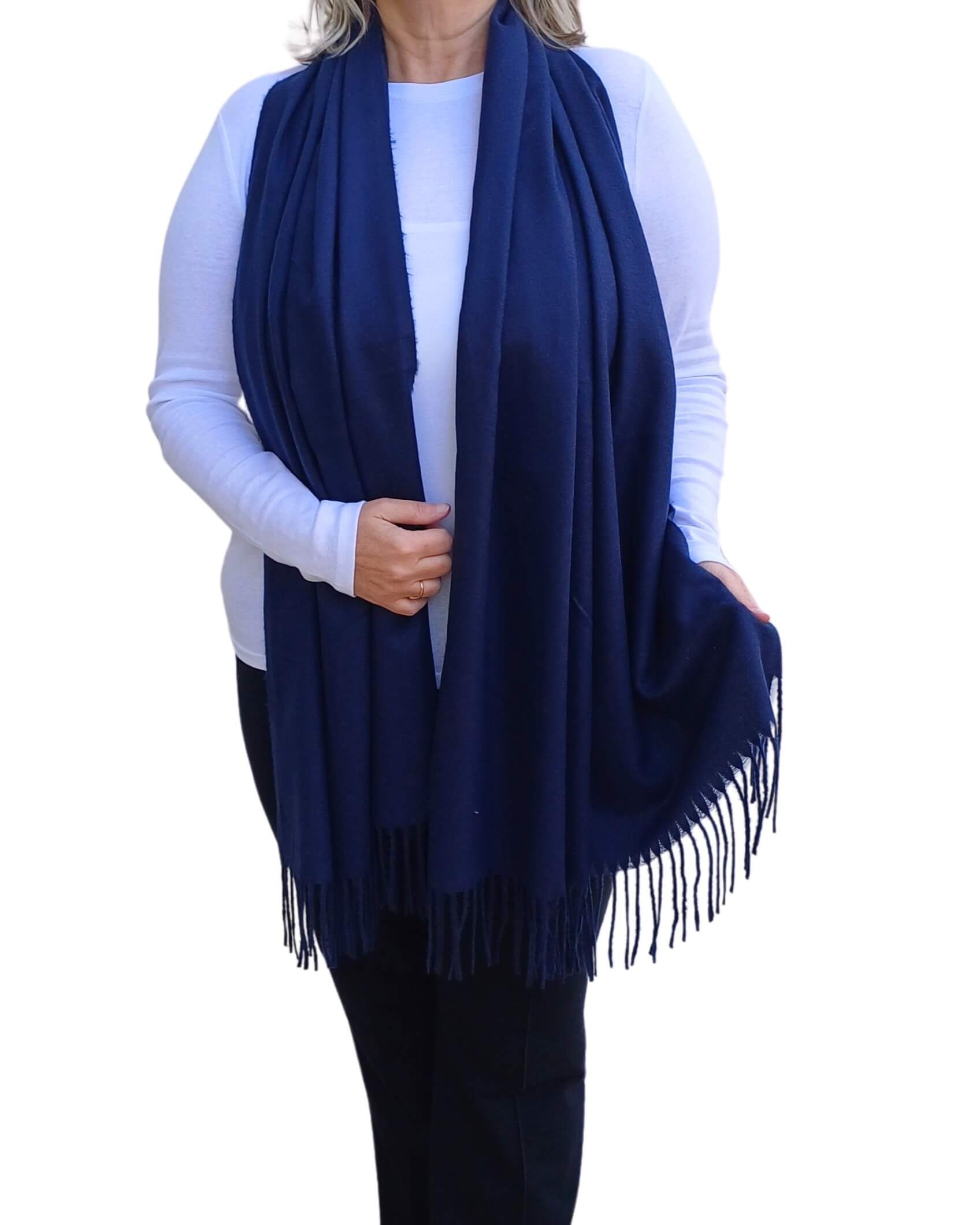 Aurora's Array: Woman models a soft, warm navy blue wool blend scarf with fringed edges, draped around her neck and shoulders.