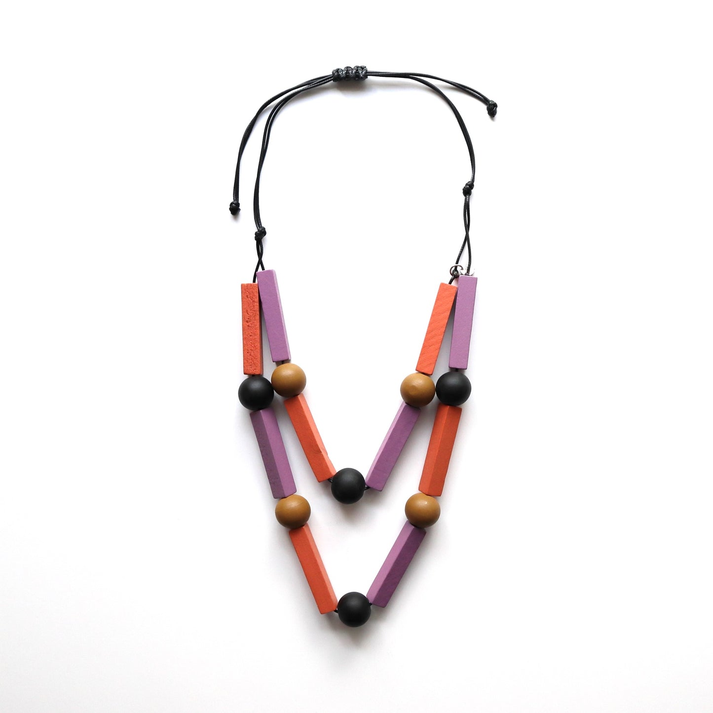 Bold, geometric necklace with black cord, featuring matte lavender and orange rectangular wooden beads, and smooth tan and black round wooden beads.