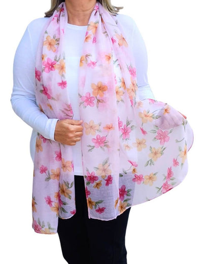 Aurora's Array: Woman models a soft, lightweight light pink scarf with a pink and orange floral print.