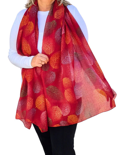 Lightweight red oversized scarf with autumn leaf pattern, modelled on white background