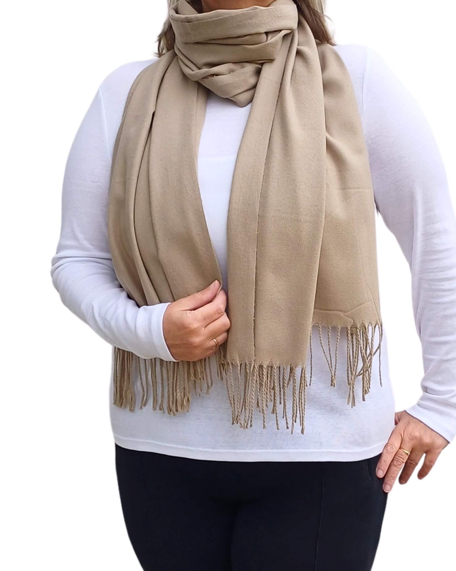 Aurora's Array: Woman models a soft, warm taupe wool blend scarf with fringed edges, wrapped around her neck.