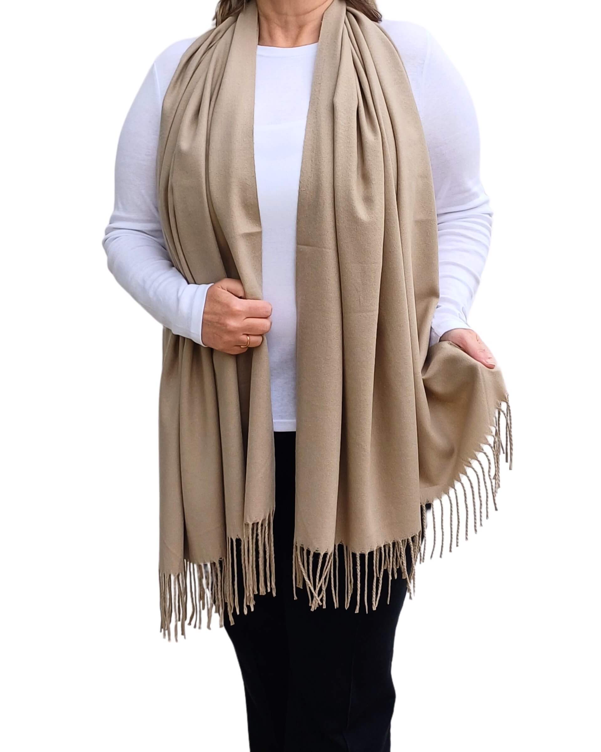 Aurora's Array: Woman models a soft, warm taupe wool blend long scarf with fringed edges, wrapped around her neck.