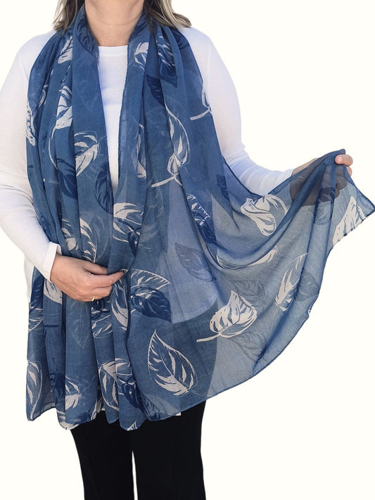 Aurora's Array: Woman models a soft, lightweight oversized blue scarf with a large white leaf print.
